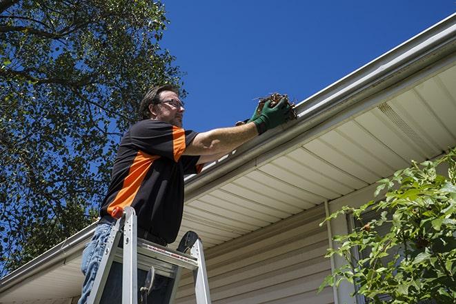 a worker using a ladder to fix a damaged gutter in Agua Dulce, CA